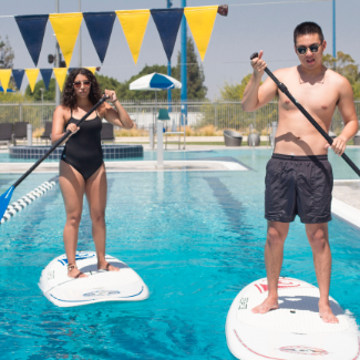 man and woman on stand up paddleboard in pool