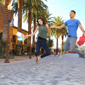 man and woman jumping in riverside plaza