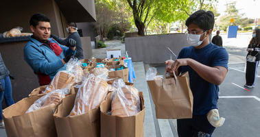 Students line up to receive a bag of groceries from R'Pantry as they set up in the back of the Arts Building 